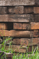 Stack of many old wooden railroad ties or wood sleepers with blur grass on foreground in vertical frame