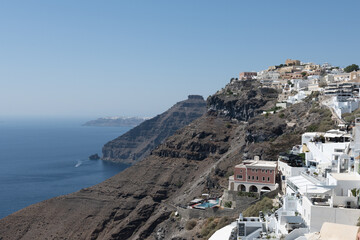 Obraz premium White top of buildings in Santorini, Greece with blue sky in a sunny warm day in July 2021.