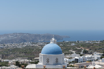 White and blue top of buildings in Pyrgos Santorini, Greece with blue sky in a sunny warm day in July 2021.