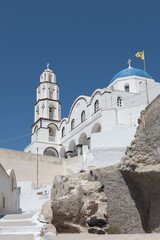 White and blue top of buildings in Pyrgos Santorini, Greece with blue sky in a sunny warm day in July 2021.
