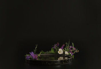 Black podium on the black background with flowers. Podium for product, cosmetic presentation....