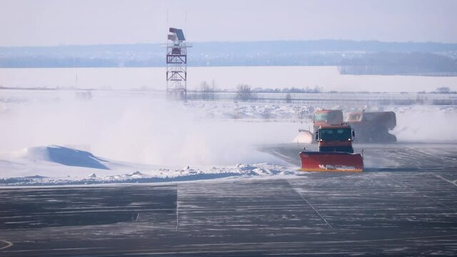 Snowplow trucks clear snowdrifts after a heavy storm blizzard at winter airport. The concept of changing weather conditions and flight delays