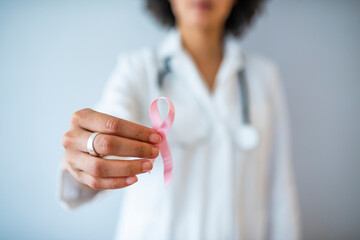 Doctor with pink ribbon and stethoscope on white background, closeup. Breast cancer awareness. Female Doctor Holds Pink Ribbon, International Breast Cancer Day October 7 - Image - obrazy, fototapety, plakaty