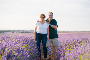 romantic lifestyle portrait of senior hispanic couple happy and relaxed at lavender flowers field enjoying retirement and celebrating aging together