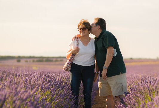 romantic lifestyle portrait of senior hispanic couple happy and relaxed at lavender flowers field enjoying retirement and celebrating aging together