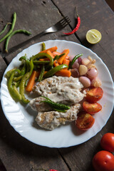 Top view of fried chicken  prepared with chicken fried in creamy white sauce and served with saute vegetables.