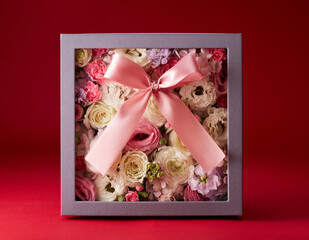 Closeup gift box full of flowers on red background