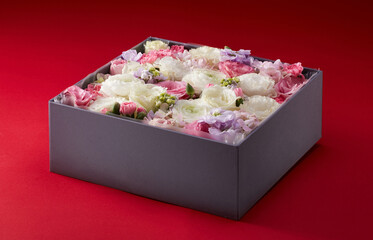 Closeup gift box full of flowers on red background