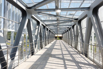 Glass pedestrian bridge with metal beams inside. Perspective perspective.
