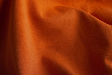 Texture of knitted fabric with waves. Orange cotton background. Fiber surface. Canvas backdrop.