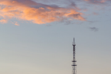 Communication tower against the background of sunset clouds
