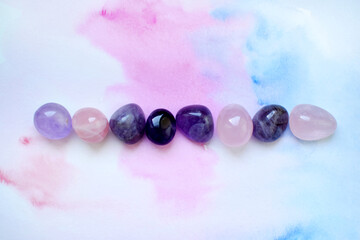 Gems of various colors. Amethyst and rose quartz on blue-pink background.