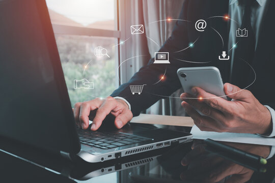 The man uses a laptop computer and mobile phone to send Digital marketing, social media advertisements, E-commerce, online shopping, IoT Internet of Things concept