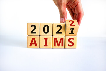 Business concept of planning 2022 aims new year. Businessman turns a wooden cube and changes words 'Aims 2021' to 'Aims 2022'. Beautiful white background, copy space. Business, 2022 aims concept.