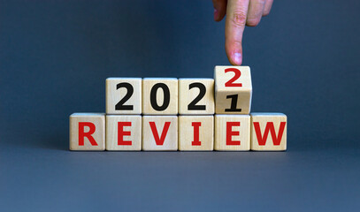 2022 review new year symbol. Businessman turns a wooden cube and changes words 'Review 2021' to...