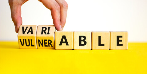 Vulnerable or variable symbol. Businessman turns wooden cubes and changes the word Vulnerable to...