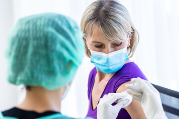 Women wearing masks getting vaccinated. Concept of coronavirus, vaccination elderly woman mask who approved covid-19 vaccination at hospital. Female doctor immunizes elderly patients against the virus