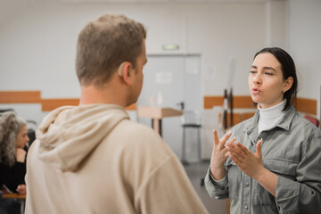 The girl and the guy talk in sign language. Two deaf students chatting in a university class.