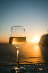 Close-up of glass with champagne wine. Sunset sky on background.