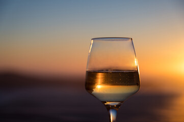 Close-up of glass with champagne wine. Sunset sky on background.
