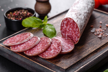 Spanish dried sausage salami on a dark concrete background