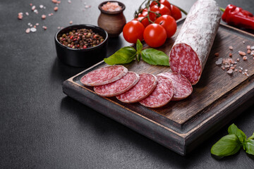 Spanish dried sausage salami on a dark concrete background
