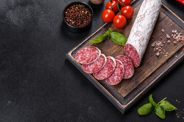 Spanish dried sausage salami on a dark concrete background
