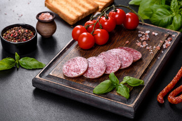 Spanish dried sausage salami on a dark concrete background
