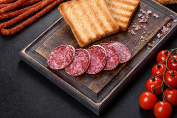 Spanish dried sausage salami on a dark concrete background
