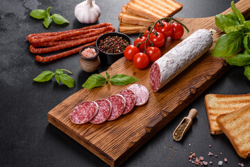 Spanish dried sausage salami on a dark concrete background