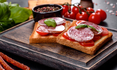 Spanish dried sausage salami on a dark concrete background