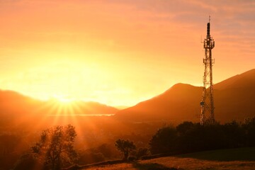 Telecommunication mast on golden sunset background in the mountains. Wonderful sunset in the Lake District (Keswick)	