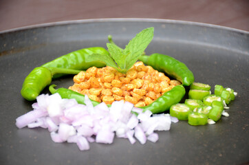 closeup the fried yellow bengal gram lentils with mint ,green chilly, sliced onion, over out of focus black brown background.