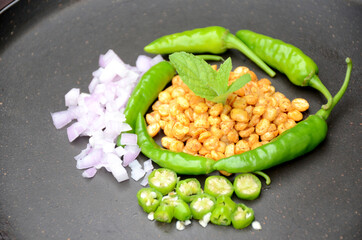 closeup the fried yellow bengal gram lentils with mint ,green chilly, sliced onion, over out of focus black background.