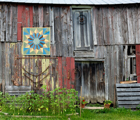 Old barn with "barn quilt" and farming artifacts on wall in western Virginia © Gerry