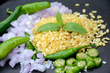 closeup the fried yellow gram split lentils with mint ,green chilly, sliced onion, over out of focus black background.