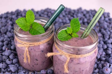 Blueberry smoothies in jars on a background of blueberries.