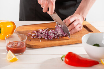 Close-up on chef's hands cutting onion with a santoku knife