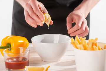 Hands squeezing a lemon slice into a bowl with ingredients