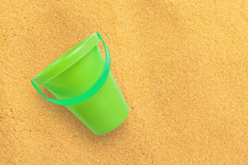 Fototapeta na wymiar Close up view green sand bucket isolated on sand beach. added copy space for text.