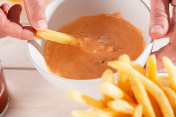 Man dipping French fries into homemade andalouse sauce