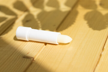 Fototapeta na wymiar hygienic lipstick on a wooden background in a white case