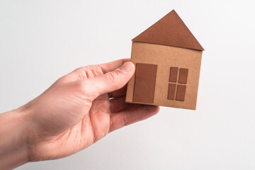 Hand holding a paper house on white background