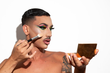 portrait of beautiful drag queen applying makeup with white background