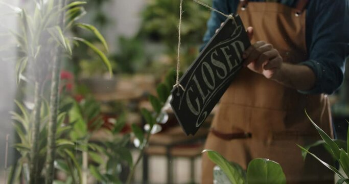 Flower shop employee flipping wooden board sign on glass entrance door. Small business, entrepreneurship concept 4k footage