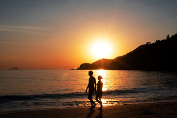 silhueta de casal caminhando em por do sol na praia de Maresias