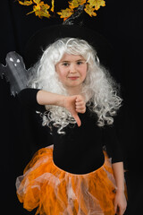 A cheerful girl in white wig and a witch costume on a black background with a ghost behind her...