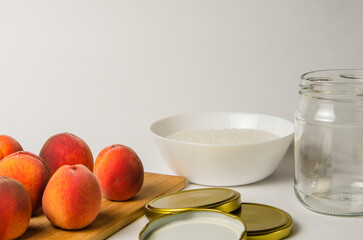 whole peach fruits are laid out on a white background on a wooden board, prepared for conservation in a glass container