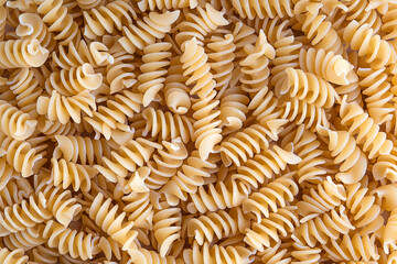 Background or backdrop made of fusilli commonly known as rotini variety of pasta that are formed...