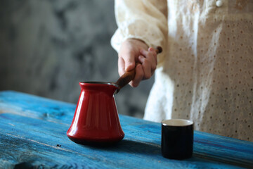 hand holding a red coffee pot on blue wooden table